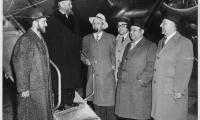Photograph of Rabbi Eliezer Silver standing on the stairs to an airplane surrounded by other individuals 