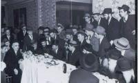 Picture of Rabbi Eliezer Silver Speaking (Seated) Surrounded by a Large Group of Men